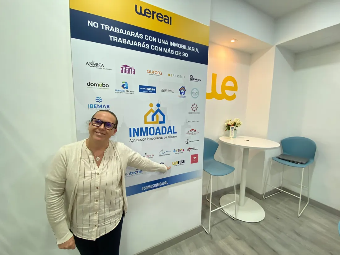 Carolina Sánchez López junto al panel de INMOADAL con las inmobiliarias de la red, entre ellas Wereal