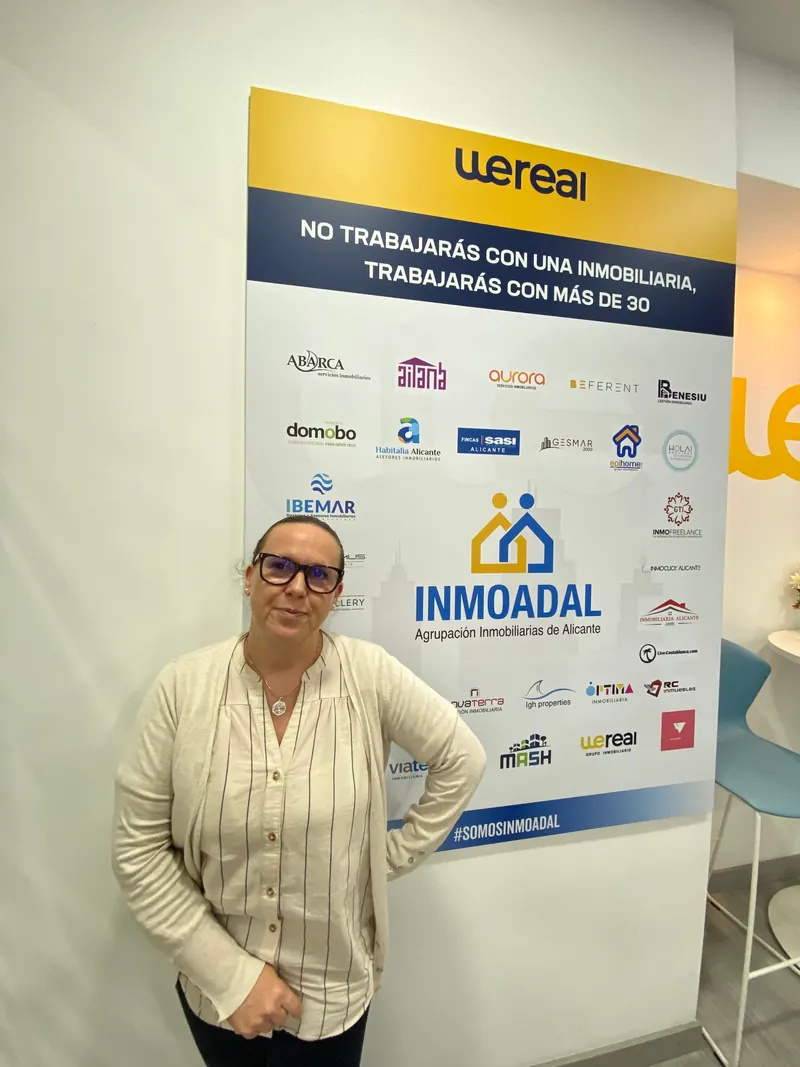 Carolina Sánchez López junto al panel «No trabajarás con una inmobiliaria, trabajarás con más de 30» de Wereal e INMOADAL