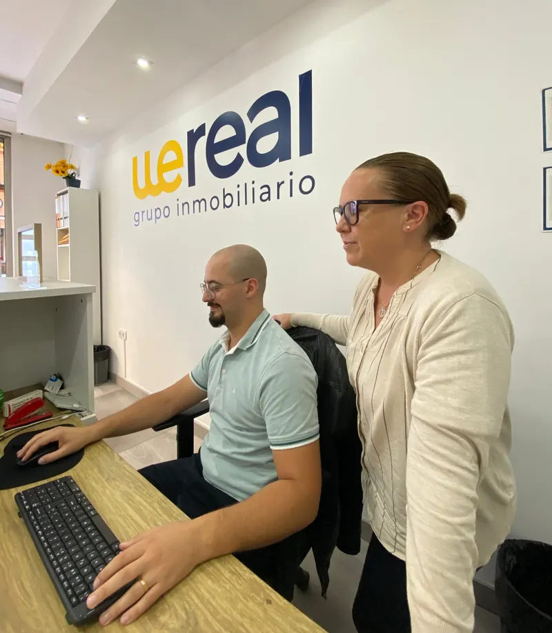 Carolina Sánchez López junto a un compañero de Wereal revisando una operación en el ordenador